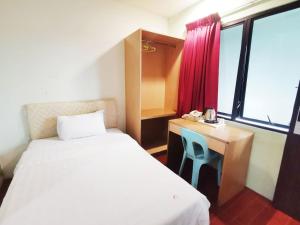 Habitación con 2 camas, escritorio y ventana. en Homestay Kuching Hotel, en Kuching