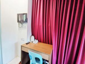 einem roten Vorhang neben einem Schreibtisch mit einem blauen Stuhl in der Unterkunft Homestay Kuching Hotel in Kuching