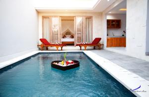 a pool in the middle of a room with red chairs at The Awandari Villas Seminyak - CHSE Certified in Seminyak