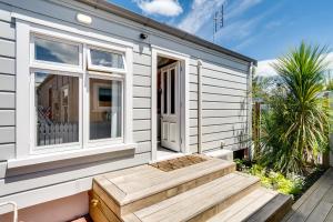 a tiny house with a wooden staircase leading to the door at Ahuriri Studio Cottage in Napier