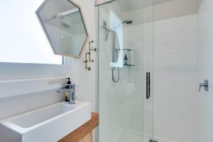 La salle de bains est pourvue d'une douche, d'un lavabo et d'un miroir. dans l'établissement Ahuriri Studio Cottage, à Napier