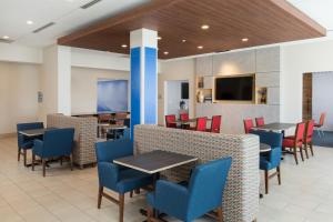 a dining room with tables and chairs and a tv at Holiday Inn Express Visalia-Sequoia Gateway Area, an IHG Hotel in Visalia