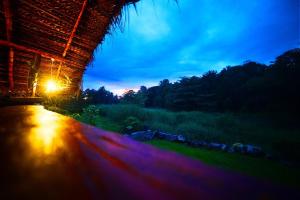 a night view of a hut with a light on the road at Aliya Riverside & Safari Resort in Udawalawe