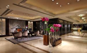 a lobby with a table and chairs and flowers in vases at The Landis Taipei in Taipei