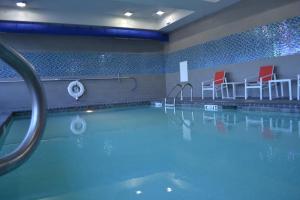 a swimming pool with red chairs and a swimming pool at Holiday Inn Express Hotel & Suites Knoxville by IHG in Knoxville