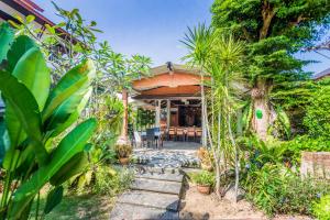 a house with a garden with trees and plants at Monaburi Boutique Resort in Rawai Beach