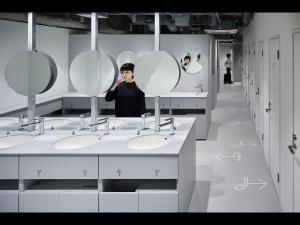 a man standing in a bathroom with sinks and mirrors at nine hours Suidobashi in Tokyo