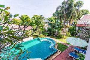 a swimming pool in a yard with an umbrella at Monaburi Boutique Resort in Rawai Beach