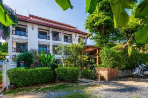 a building with bushes and trees in front of it at Monaburi Boutique Resort in Rawai Beach