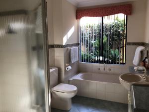 a bathroom with a tub and a toilet and a sink at Alfred Cove Short Stay in Perth