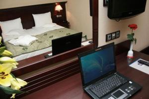 Schlafzimmer mit einem Bett und einem Schreibtisch mit einem Laptop in der Unterkunft Hotel Rapsodia City Center in Botoşani