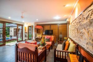 a living room with chairs and a couch and a tv at Villa Saffron Seminyak Bali in Seminyak