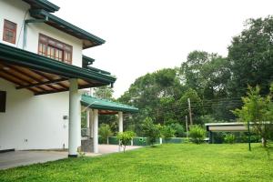 una casa con un patio verde al lado de un edificio en Seven Luck Palace en Kandy