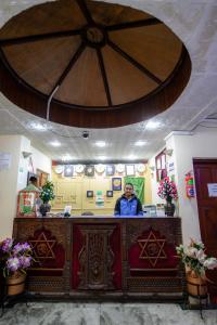 Un homme debout derrière un comptoir dans une pièce fleurie dans l'établissement Hotel Pomelo House, à Katmandou