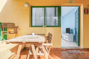 una mesa de madera y sillas en una habitación con ventana en 8211 Bungalow Costa Calma Wifi, en Costa Calma