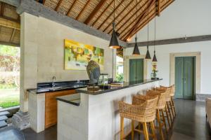 an outdoor kitchen with a bar and chairs at Villa Themma Jungle - Sumptuous 3BR Luxury Villa with Majestic Jungle View North of Ubud in Ubud