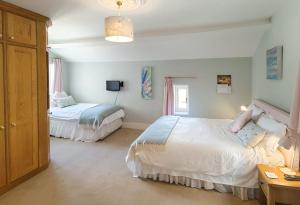 1 dormitorio con 2 camas, mesa y TV en Eastwrey Barton Country House, en Lustleigh