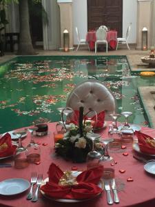 una mesa con mantel rojo y una piscina de agua en Riad Shama Suites & Spa en Marrakech