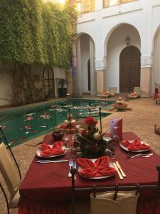 una mesa con mantel rojo y una piscina de agua en Riad Shama Suites & Spa, en Marrakech