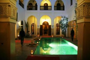 ein Schwimmbad in einem Gebäude mit Leuten, die ihn umlaufen in der Unterkunft Riad Shama Suites & Spa in Marrakesch