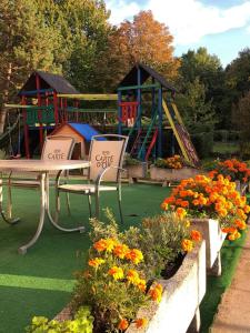 un parque infantil con mesa, sillas y flores en InterSport Hotel, en Stupava