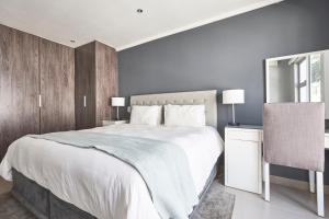 a bedroom with a large white bed and a chair at The Residency Hurlingham in Johannesburg