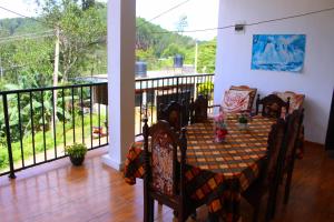 a dining room with a table and chairs on a balcony at Thilini homestay in Ella