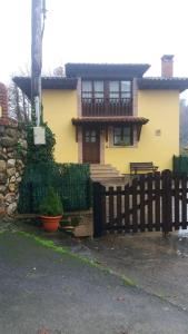 une maison jaune avec une clôture en bois devant elle dans l'établissement CASA RURAL LA MONTESINA, à Cangas de Onís