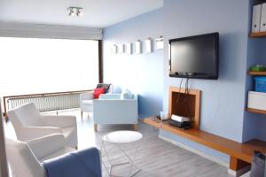 een woonkamer met witte stoelen en een flatscreen-tv bij Thalassa 15 in Zeebrugge