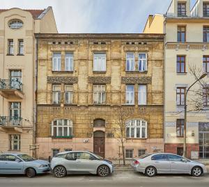 trzy samochody zaparkowane przed ceglanym budynkiem w obiekcie Kurkowa GamaHome Cozy Apartments w Krakowie