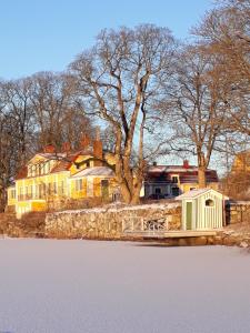 Una gran casa amarilla con un árbol delante. en Gåvetorps Gård, en Alvesta