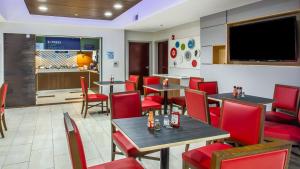 a restaurant with red chairs and tables and a flat screen tv at Holiday Inn Express & Suites - Olathe South by IHG in Olathe +16 photos