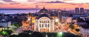 a city skyline at night with a large building at Hotel Dez De Julho in Manaus