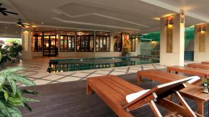a swimming pool in a building with wooden benches and a pool at Pattaya Loft in Pattaya Central