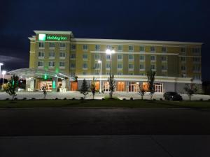 a large yellow hotel with a green sign on it at Holiday Inn Covington, an IHG Hotel in Covington