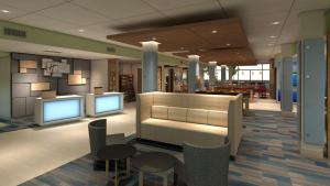a lobby with two monitors and chairs and tables at Holiday Inn Express & Suites - Olathe South, an IHG Hotel in Olathe