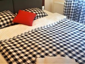 a black and white checkered bed with a red pillow at Jaworowa Chata in Wisła