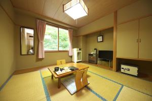 sala de estar con mesa y TV en Shiga Swiss Inn, en Yamanouchi