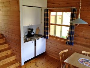 cocina con paredes de madera, mesa y ventana en Fjorden Campinghytter, en Geiranger