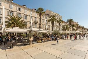 um grupo de pessoas andando em torno de uma rua com mesas e guarda-chuvas em Olivia Luxury Rooms em Split
