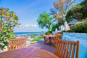 une terrasse en bois avec une table et des chaises, ainsi que la plage dans l'établissement Baan Bayan - Hua Hin - SHA Extra Plus, à Hua Hin