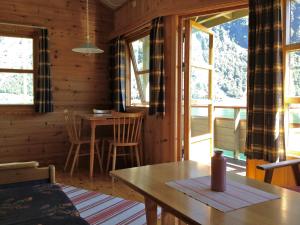 comedor con mesa, sillas y ventanas en Fjorden Campinghytter, en Geiranger