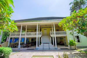 ein gelbes Haus mit Treppen, Tischen und Stühlen in der Unterkunft Baan Bayan - Hua Hin - SHA Extra Plus in Hua Hin