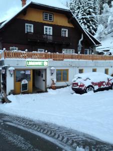 a snow covered building with a car parked in front of it at Gasthaus Luggwirt in Gnesau