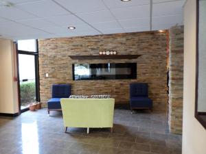 a lobby with two chairs and a brick wall at Travelodge by Wyndham Cleveland Lakewood in Lakewood