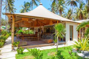 ein Haus mit einer Terrasse und einem Zelt in der Unterkunft Gili Tenda in Gili Trawangan