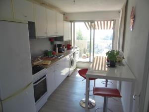 eine Küche mit weißen Schränken, einem Tisch und einem Fenster in der Unterkunft La Madonette in Nizza