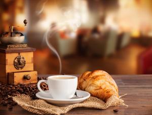 una taza de café y un cruasán sobre una mesa en JaHotel, en Geldern