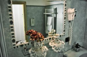a bathroom with a mirror and a vase with flowers at Hotel Victoria in Taormina