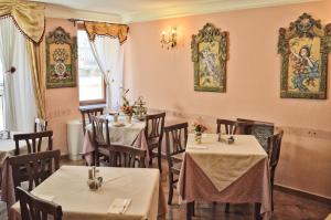 a dining room with tables and chairs and paintings on the walls at Hotel Victoria in Taormina